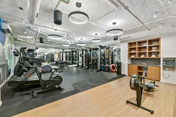 A gym with weights and other exercise equipment on a wooden floor